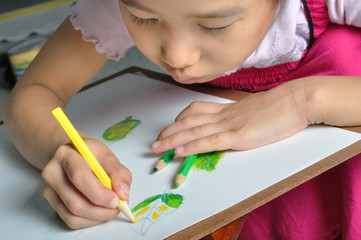 closeup little asian girl hand draw her  picture with color penc