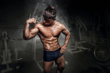 Fototapeta na wymiar Bodybuilder man showing his biceps in gym