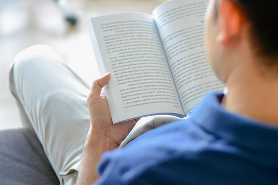 Young man reading book while sitting on the couch