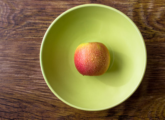 Apple in water drops on a plate