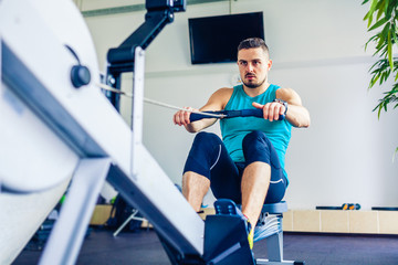 Crossfit instructor at the gym doing Rowing Exercise