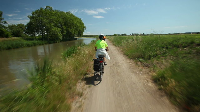 Slow motion - Retired couple cycling beside river on holiday