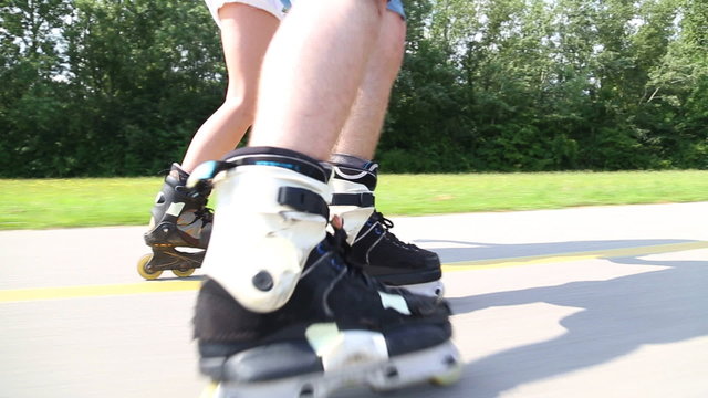 Happy young couple rollerblading on a wonderful sunny day in park, view of legs