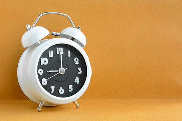White retro alarm clock on light brown background 