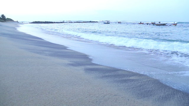 View of waves and fishermen in Mirissa. These traditional fishermen find it harder to make a living from poor fishing catches.