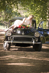 Young couple stopped on side of dirt road with vintage car