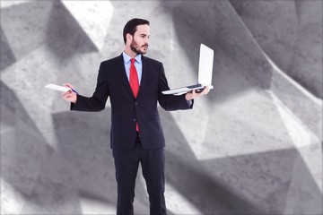 Composite image of handsome businessman holding his laptop