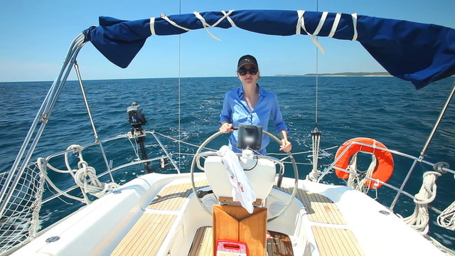 Woman at wheel steering sailboat on Adriatic sea in Croatia