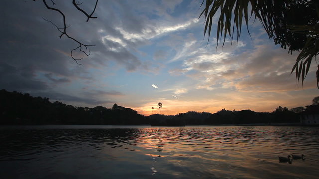 View on the Kandy lake at sunset with reflection of sky in water.