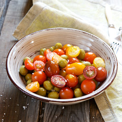 Multicolored cherry tomatoes and olives salad with salt