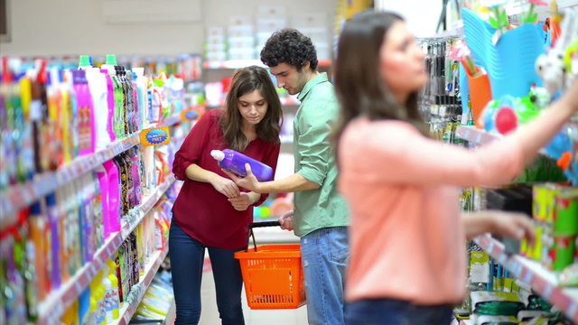 Customers choosing cleaning products in supermarket