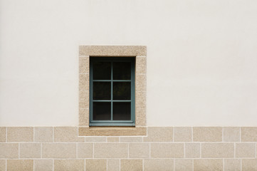 Grünes Holzfenster in Fassade mit Sockel aus Granit