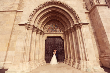 Fototapeta premium Bride and groom embracing in front of the church