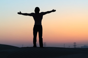 Fototapeta premium The man silhouette alone at sunset with outstretched arms