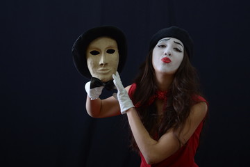 the girl is MIME holding a theatrical mask with hat