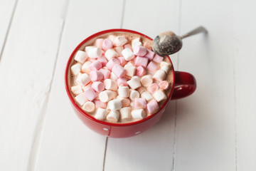 Hot chocolate with marshmallows in red cup on table
