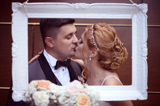 Bride and groom kissing through the frame