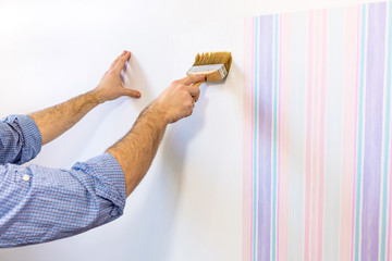 Handyman painting wall with background glue for a wallpaper