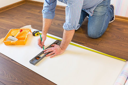 Handyman measuring wallpaper to cut