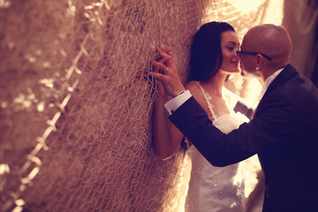 Obraz na płótnie Canvas Bride and groom against a wall with trammel