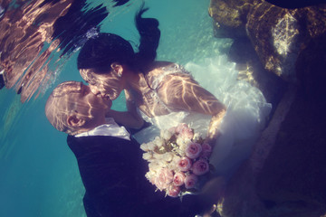 Bride and groom kissing underwater