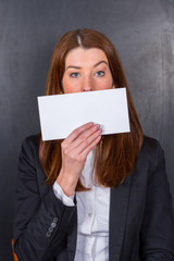 Junge Dame h&auml;lt wei&szlig;es Schild vor Mund / skeptisch