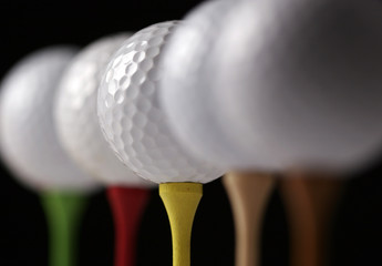 Several golf balls on tees, one in focus