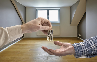 Realtor giving house key to buyer in empty room