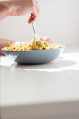 Man Twirling Fettuccine Pasta on Bowl Using a Fork