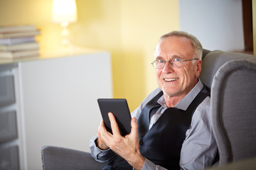 Senior man at home reading on a e-book 3