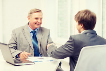 older man and young man shaking hands in office