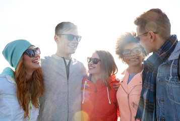 happy teenage friends in shades talking on street