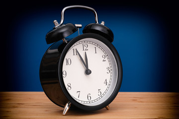 Black alarm clock against blue background