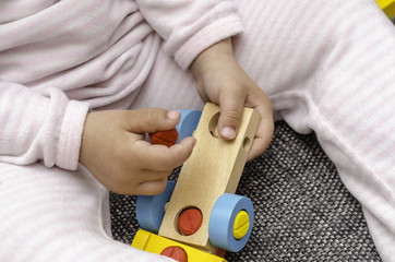 A kid is playing with a colorful wooden car.