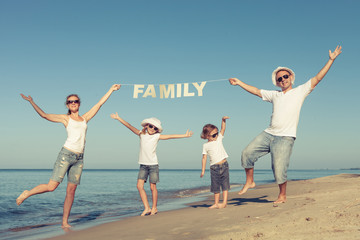 Happy family standing on the beach at the day time.