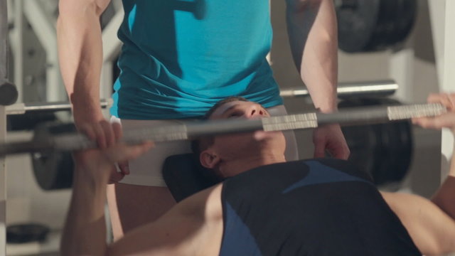 Close up of man building his muscles with personal trainer at