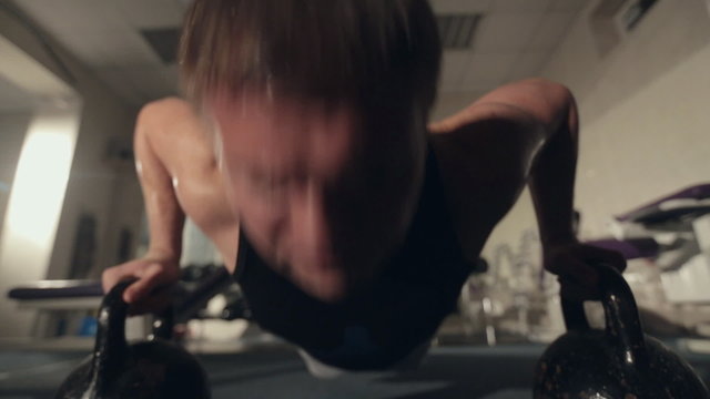 Sweaty man pushed from floor with dumbbells in the gym