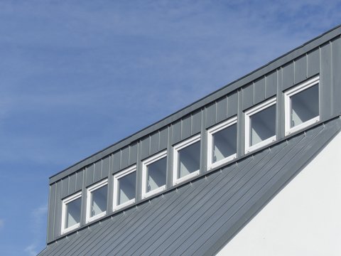 Modernes Dach und Fassade aus Zink mit Fensterreihe vor blauem Himmel im Sonnenschein in Wettenberg Krofdorf-Gleiberg bei Gie&szlig;en in Hessen