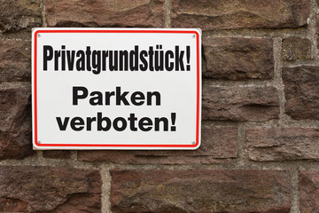 Schild - Privatgrundstück Parken verboten - an einer Steinmauer