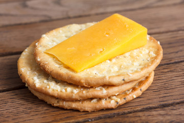 Three golden cheese crackers on wood. With cheese.