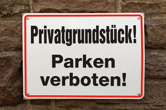 Schild - Privatgrundstück Parken verboten - an einer Steinmauer