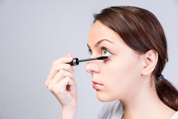 Attractive woman applying dark mascara