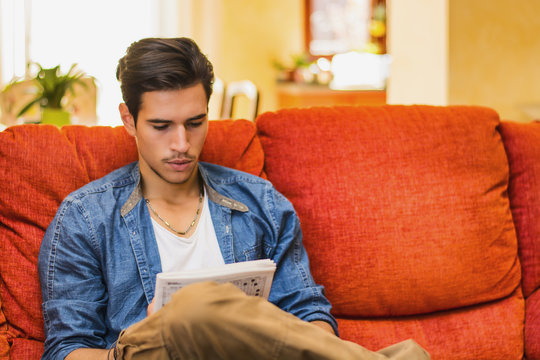 Young Man Doing A Crossword Puzzle Looking Thoughtfully At