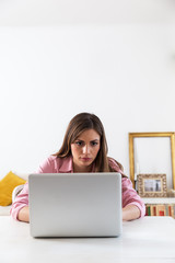 Young brunette working at her home on  laptop.