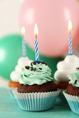 Delicious birthday cupcakes on table on bright background