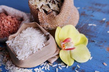 Different types of rice in sacks on wooden background