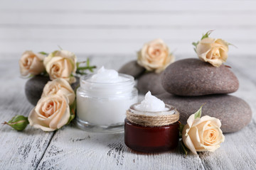 Obraz na płótnie Canvas Cosmetic cream with flowers and spa stones on wooden background