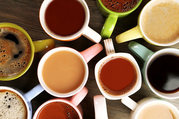 Many cups of coffee on wooden table, top view
