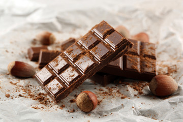 Pieces of chocolate with cocoa on parchment, closeup