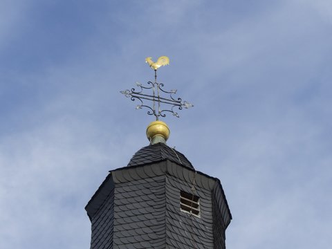 Kirchturm mit Wetterhahn vor blauem Himmel im Sonnenschein der Katharinenkirche in Wettenberg Krofdorf-Gleiberg bei Gießen in Hessen